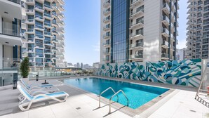 A rooftop swimming pool with lounge chairs and a decorative wall. - Free Housekeeping Visits During Your Stay - Stayshort - Relaxing 1 Bedroom in JVC That Sleeps 2 (Dubai)