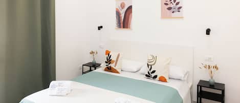 A hotel room with a bed, two bedside tables, and a wall-mounted artwork.
