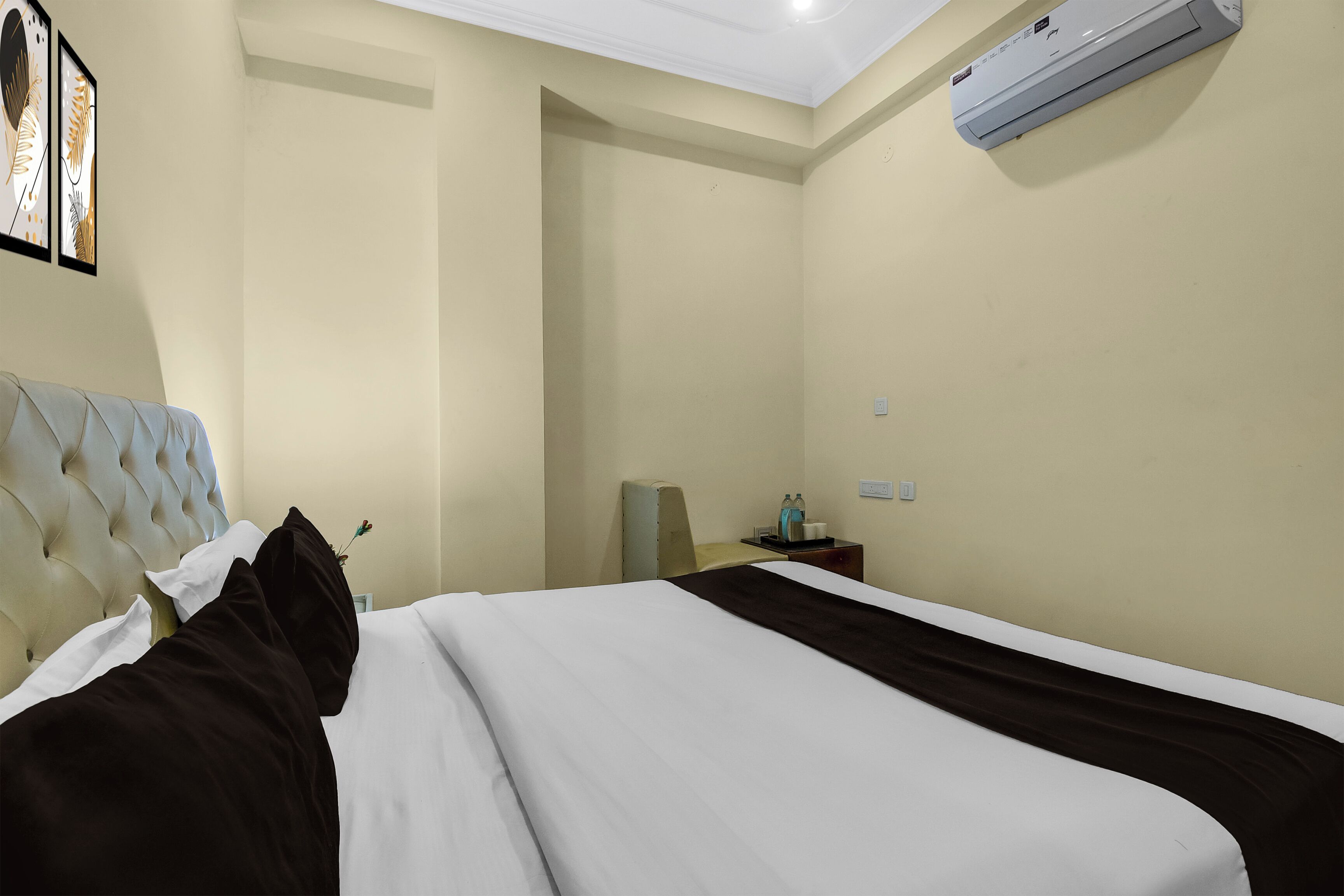 Una habitación de hotel con cama, una silla, una mesita de noche y un equipo de aire acondicionado en la pared.