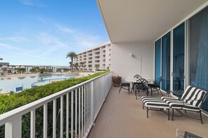 Ein Balkon mit Blick auf einen Pool, Sitzgelegenheiten im Freien und einem klaren Himmel.