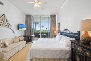 Ein Hotelzimmer mit Bett, einer Couch, einem Fernseher, einem Deckenventilator und einem Balkon mit Blick.