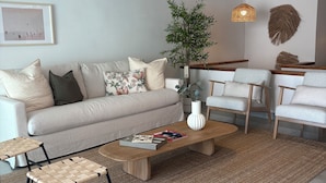 A modern living room with a sofa, coffee table, and chairs, a large plant, and a hanging light fixture. - Private Cove Salions (Tossa de Mar)