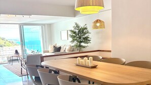 A modern dining area with a wooden table, chairs, and a hanging light fixture. - Private Cove Salions (Tossa de Mar)