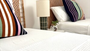 A bedroom with two beds, a bedside lamp, and a small vase with a plant. - Private Cove Salions (Tossa de Mar)