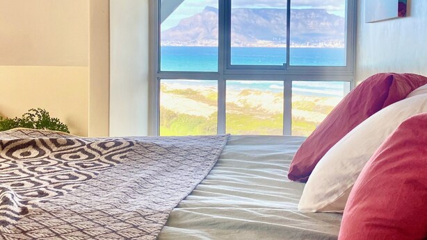Un dormitorio con un ventanal grande, una cama con ropa de cama estampada y vistas a un paisaje.