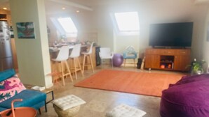 Una sala de estar con sofá, reposapiés y televisor.