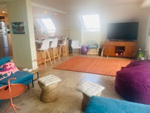 Ein Wohnzimmer mit einer Couch, einem Hocker und einem Fernseher.