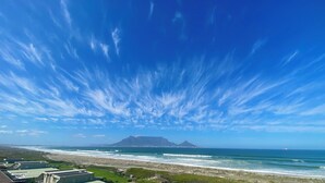 Un paisaje costero con cielo despejado, una playa y montañas a lo lejos.