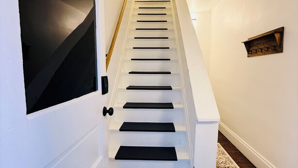 A staircase with white railings, a wooden door, and a dark wooden floor. - Renovated 2BR - Workspace - Near UC Med & Cincy (Saint Bernard)