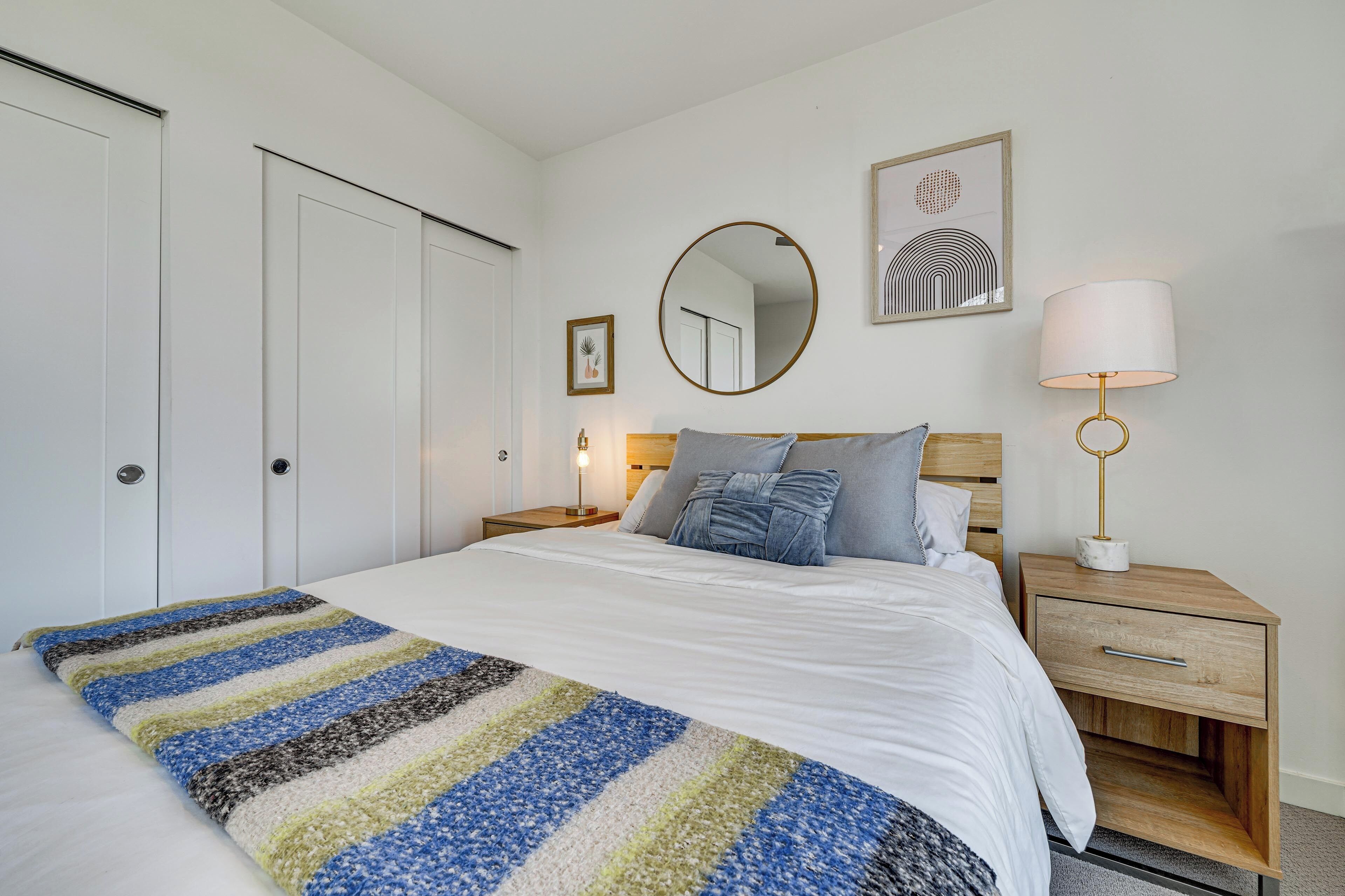 Une chambre à coucher bien rangée, avec un lit, des tables de chevet, une lampe et un miroir.