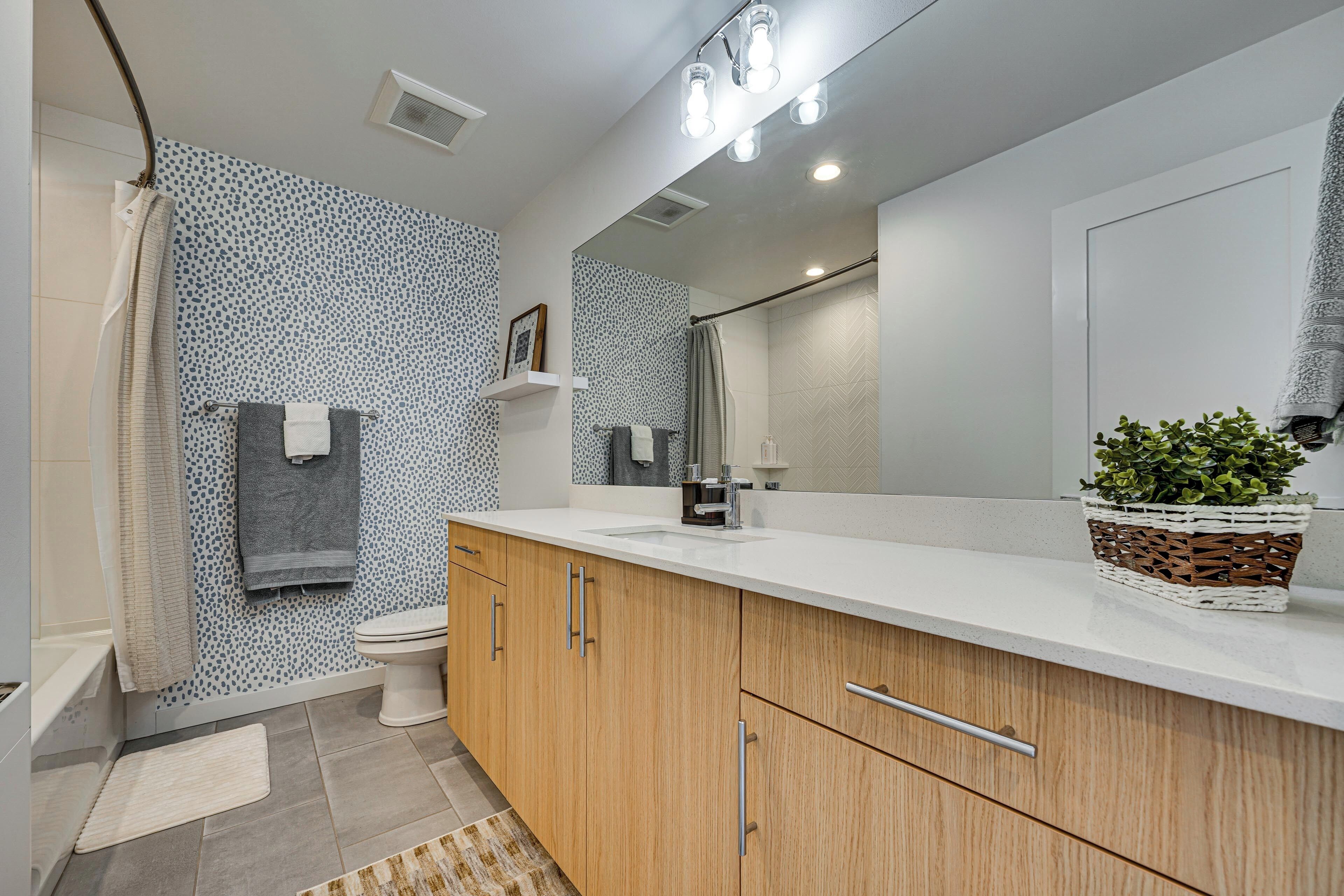 A modern bathroom with a shower, toilet, and sink.
