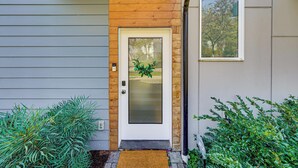 A modern house with a wooden front door, a small porch, and a window reflecting trees. - Rooftop Retreat w/ City Views: Modern Seattle Home (Seattle)