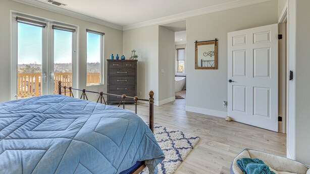 A bedroom with a bed, a dresser, a door, and a view of the outside. - LA Costa Valley Newly Remodeled Gem (Carlsbad)