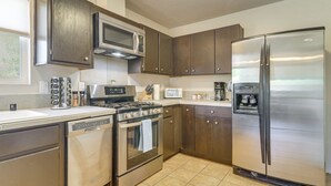 Una cocina moderna con electrodomésticos de acero inoxidable, armarios de madera oscura y piso de baldosas.