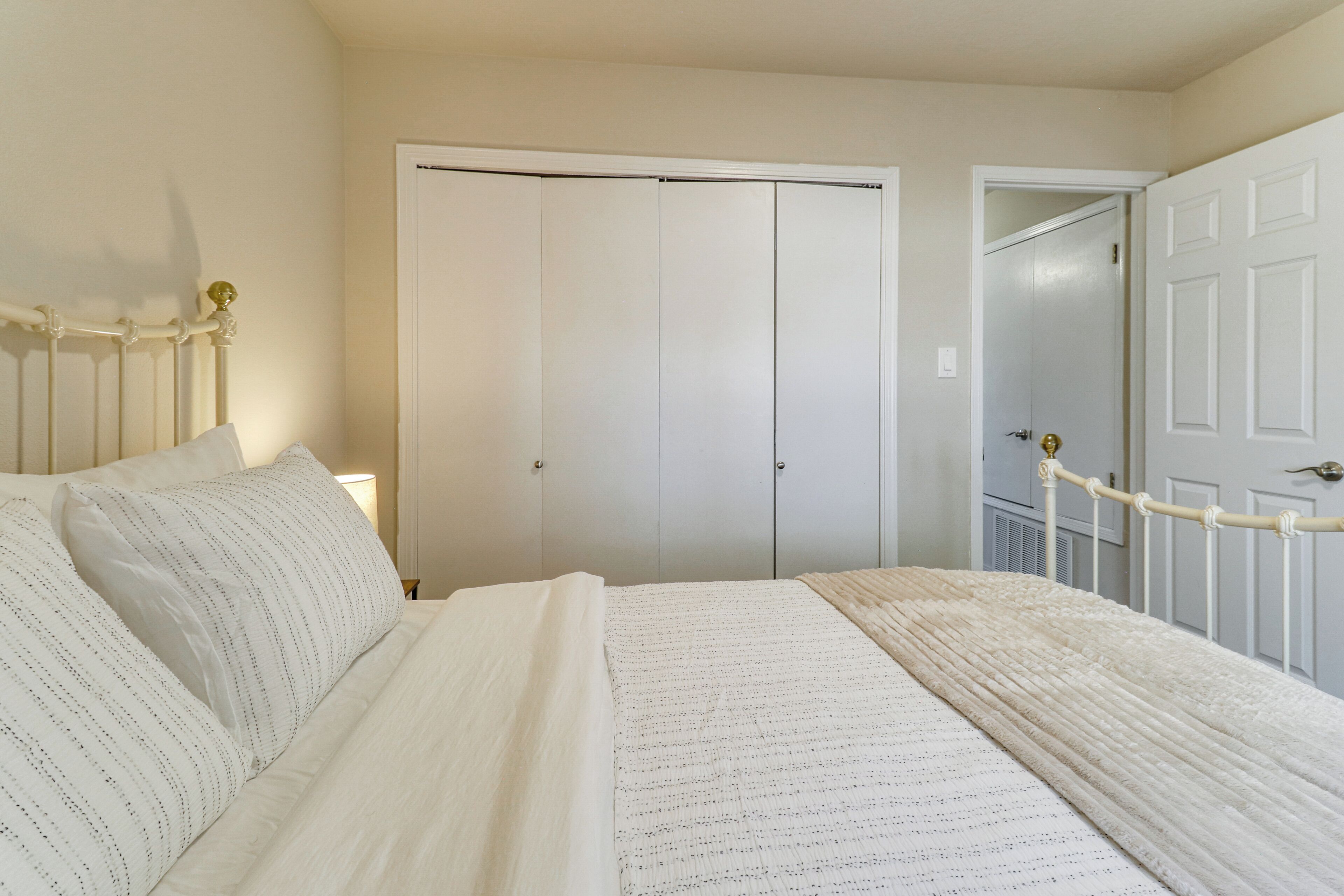 A bedroom with a bed, a wardrobe, and a door.