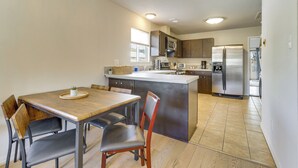 Una cocina moderna con una isla central, electrodomésticos de acero inoxidable y un comedor con una mesa y sillas de madera.