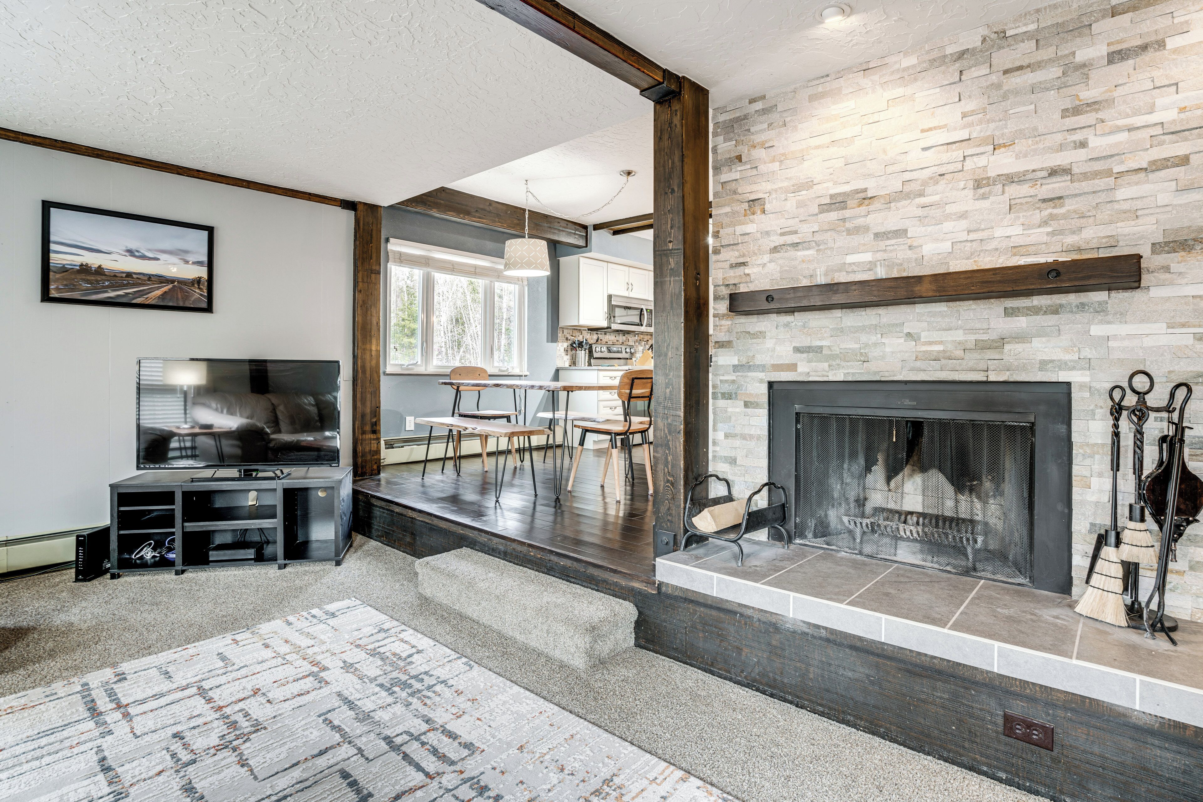 A living room with a fireplace, a television, and a dining area with chairs and a table.