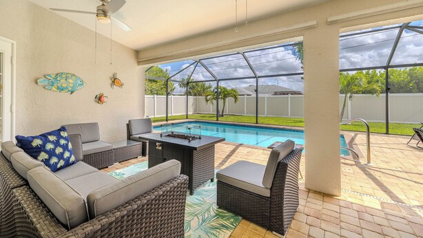 A covered patio with outdoor furniture, a pool, and a view of the backyard. - Bring your dogs and enjoy the charm of this home! 3 be- 2ba in SE Cape Coral (Cape Coral)