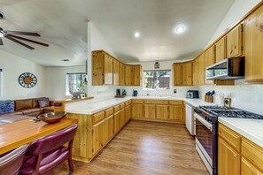 Una cocina con armarios de madera, estufa y microondas.
