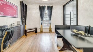 Een eetgedeelte met een tafel, stoelen, een bank en een kroonluchter.