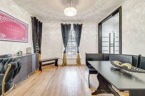 Een eetgedeelte met een tafel, stoelen, een bank en een kroonluchter.