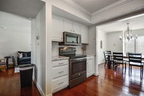 A kitchen with white cabinetry, a microwave, an oven, and a dining area with chairs and a table. - Lake Living & Game Room! Group Escape 3 Mi to HPU (High Point)