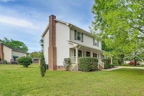 A two-story house with a brick chimney, a front porch, and a well-maintained lawn.