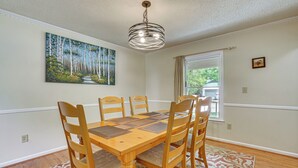 A dining room with a wooden table and chairs, a painting on the wall, a window with curtains, and a patterned rug. - Quiet Family Home w/ Yard! 9 Mi to Dtwn Greenville (Greenville)