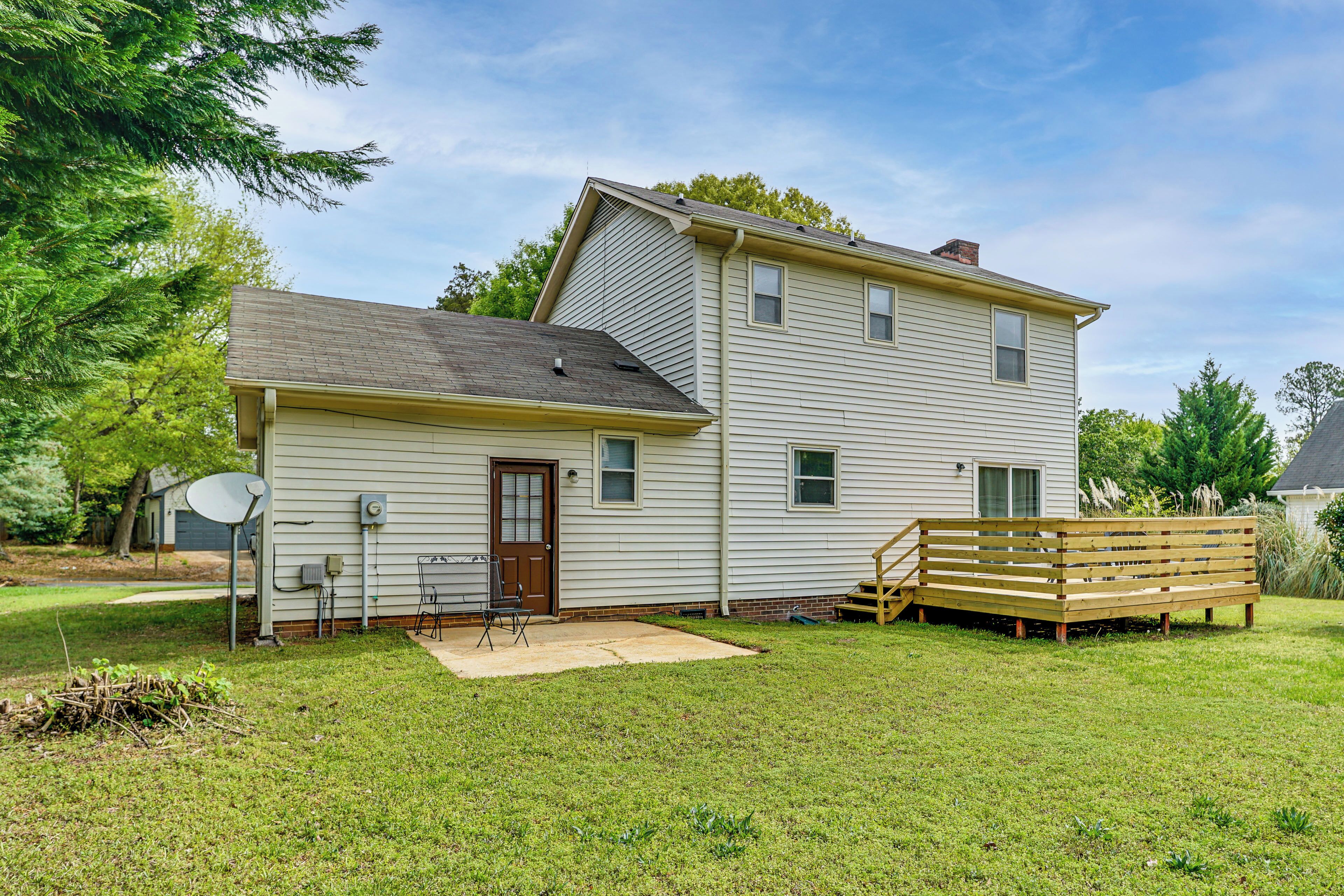 A two-story house with a front porch, a satellite dish, and a wooden deck.