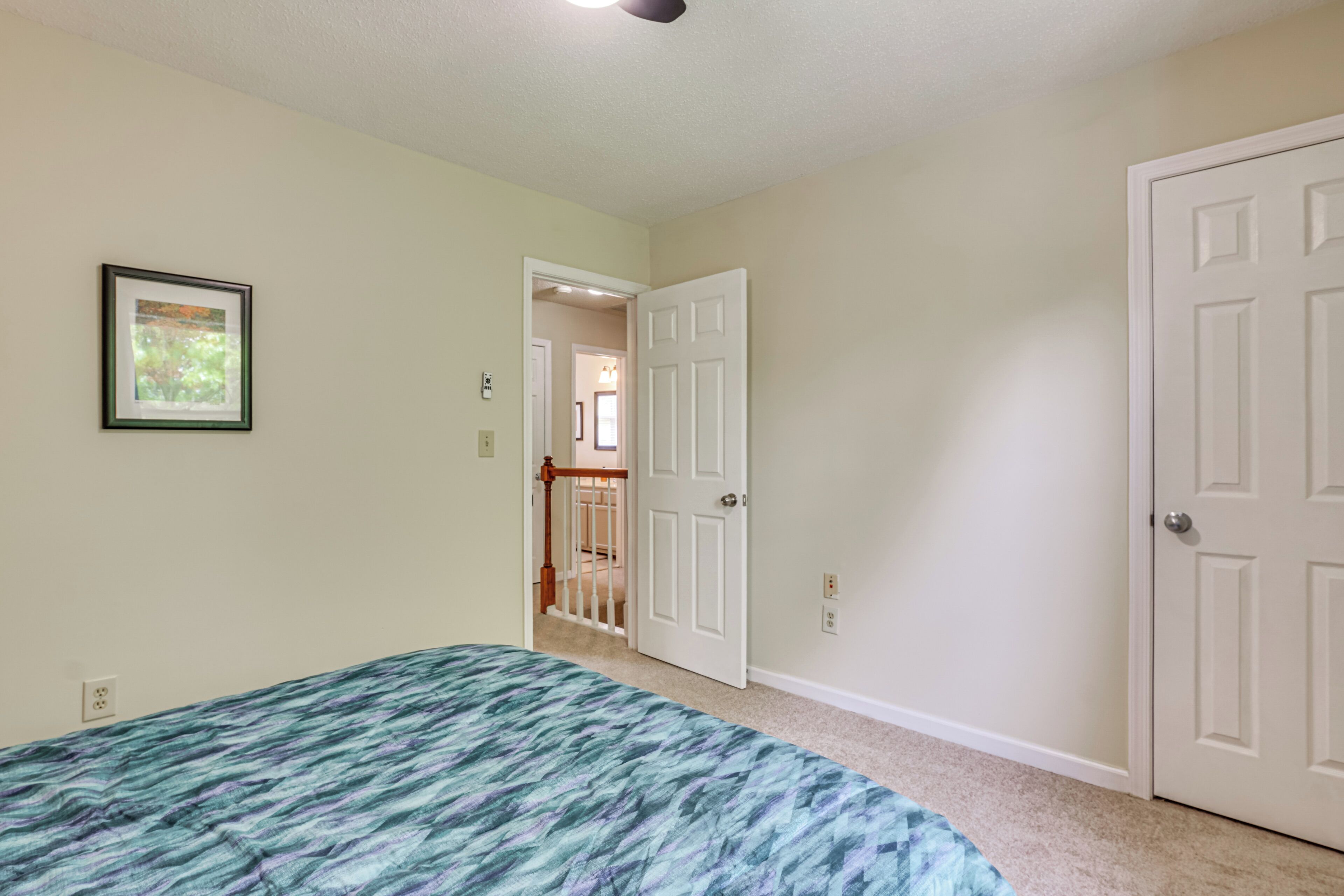Un dormitorio con cama, una puerta, un pasillo y una escalera.