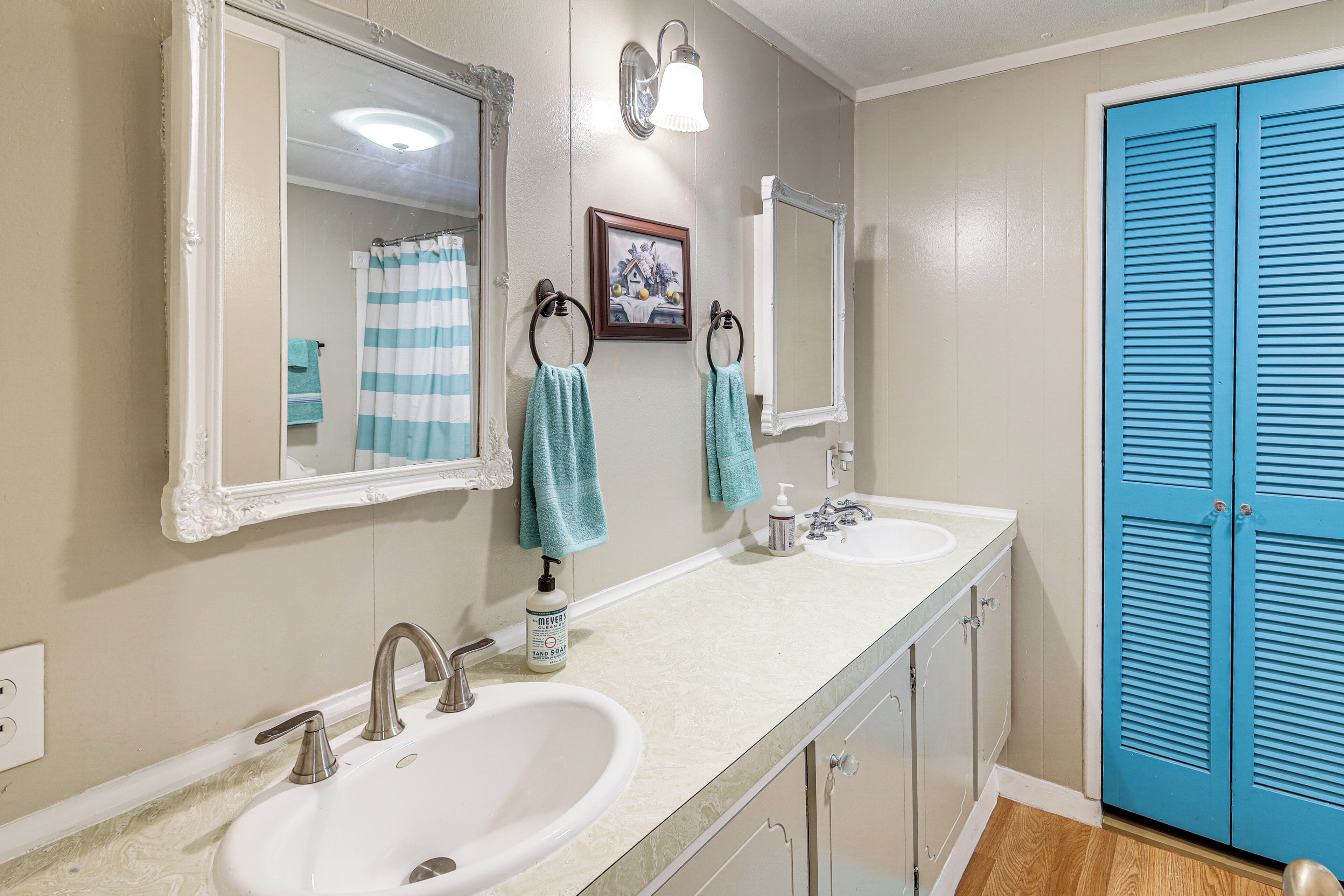 A bathroom with two sinks, a mirror, a towel rack, and a blue door.
