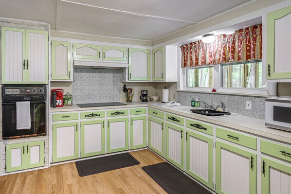 A kitchen with green cabinets, a stove, a sink, and a window with curtains. - 2 Mi to Cherokee Landing! Secluded Forest Escape (Higden)