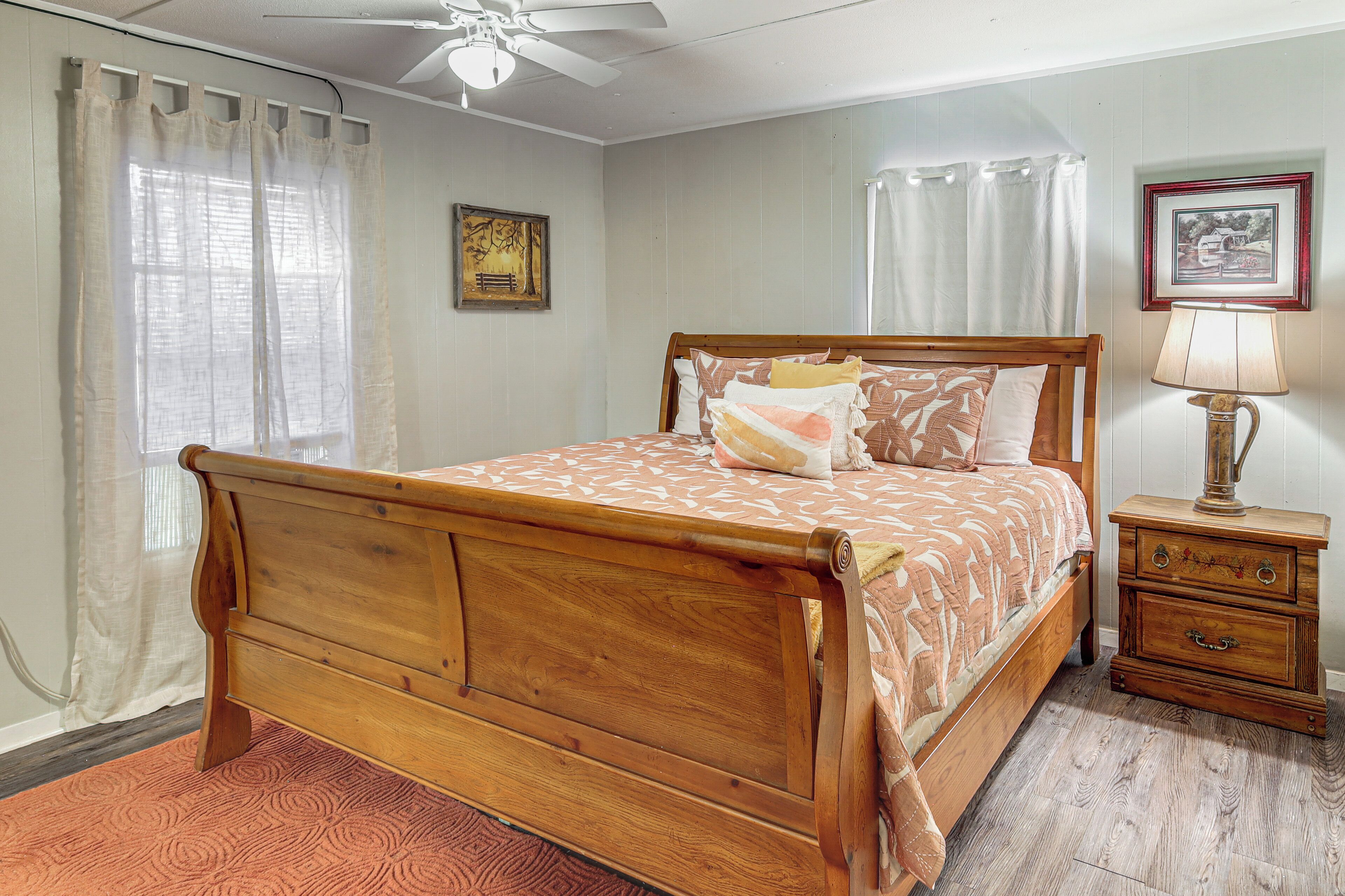 A bedroom with a wooden bed, a nightstand, a lamp, and a ceiling fan.