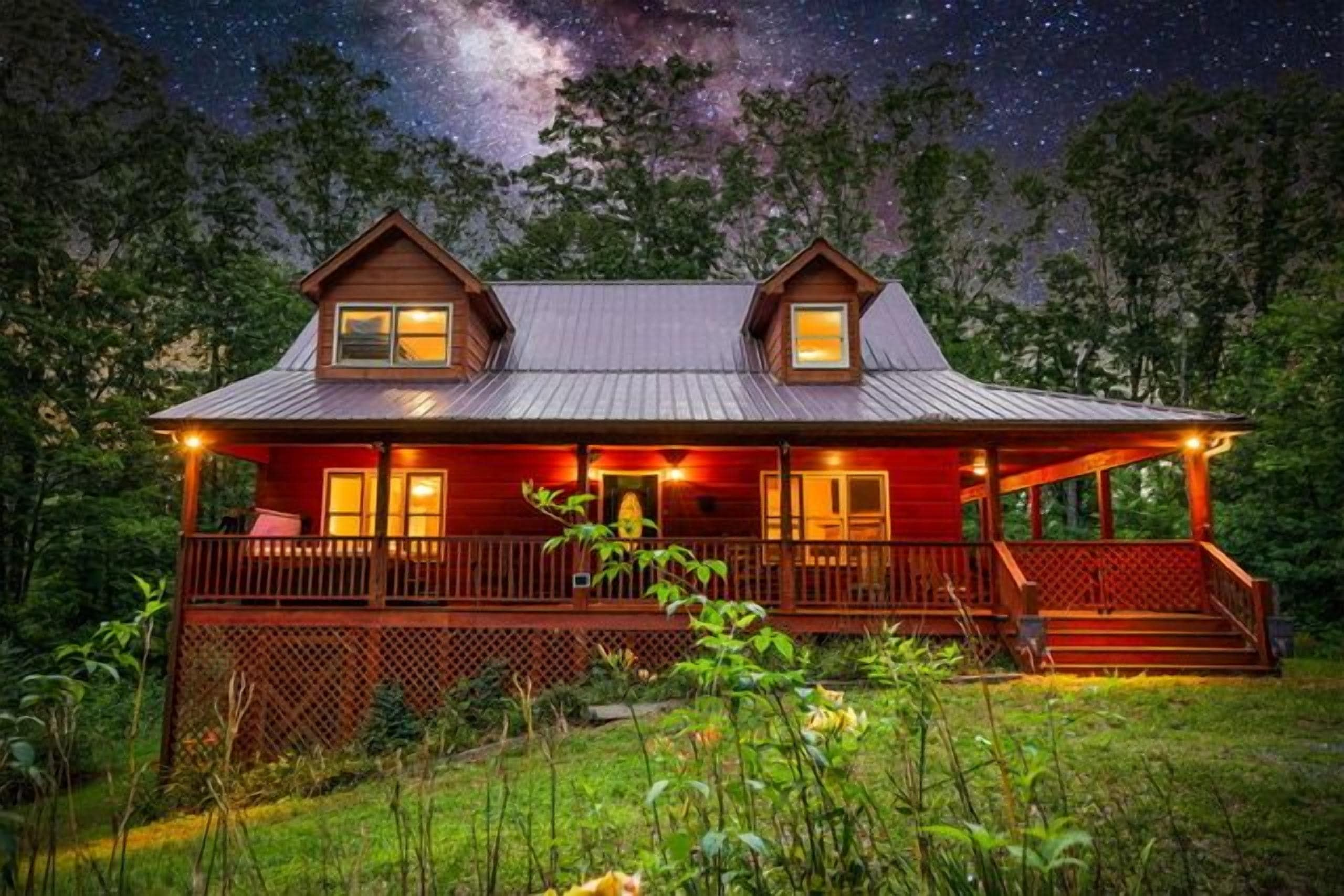 A two-story wooden cabin with a porch, surrounded by greenery.