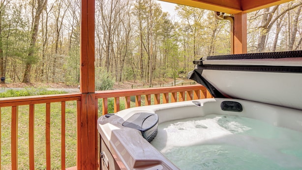 A hot tub on a wooden deck with a view of a forest. - 4 King Beds, Hot Tub, & Game Room! (Ellijay)