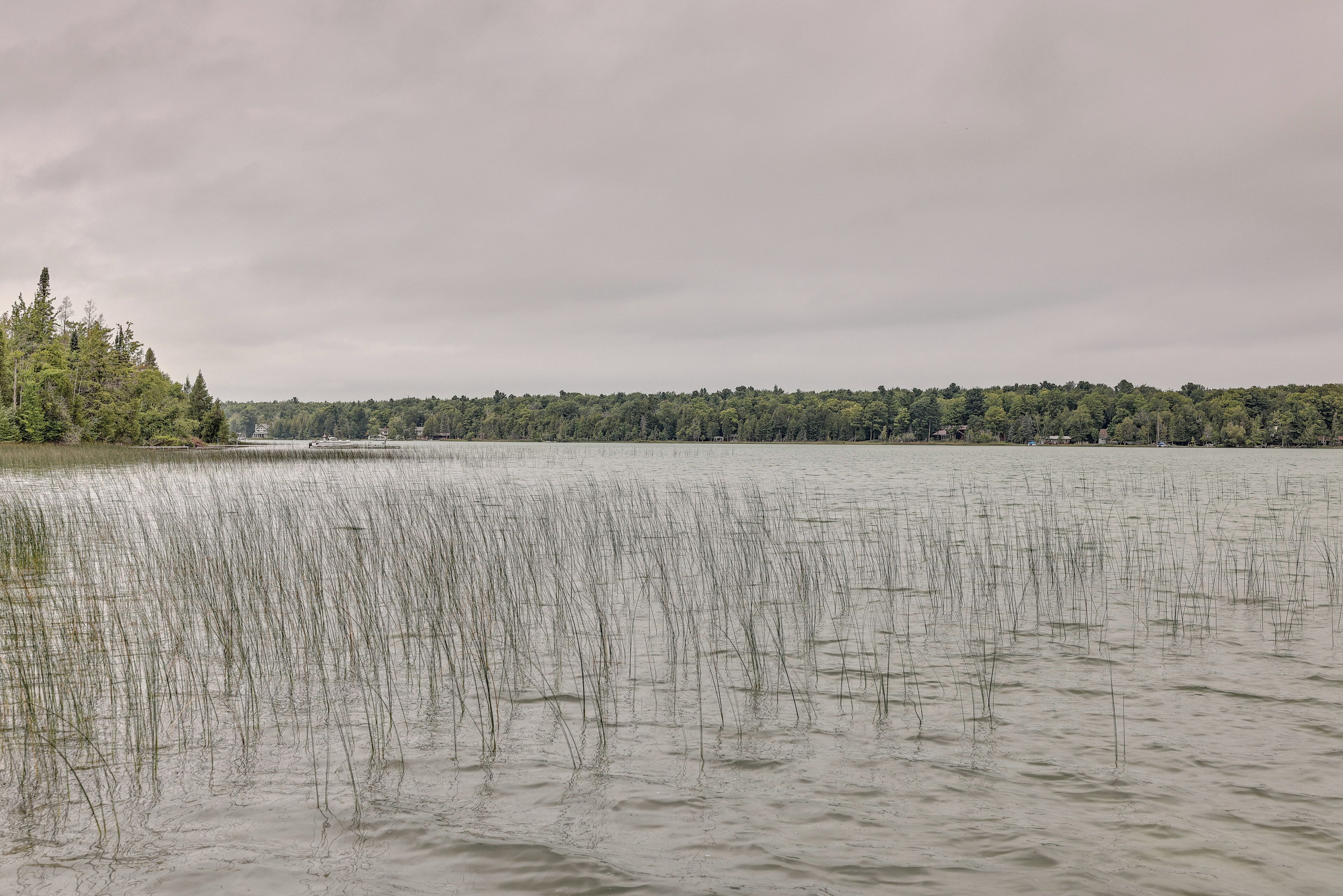 Ein See mit bewaldeter Uferlinie und einem Boot in der Ferne.