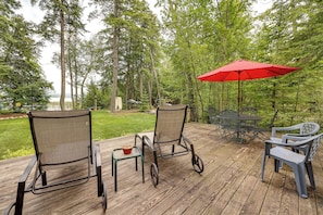A wooden deck with outdoor furniture, including chairs and a table, and a red umbrella providing shade. - On 4 Acres! Retreat w/ Lake Access in Maple City (Maple City)