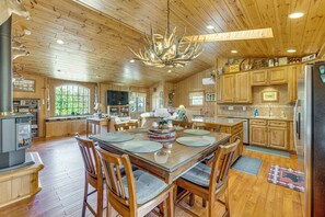 A spacious wooden interior with a large dining table, chairs, a fireplace, and a kitchen area. - On 4 Acres! Retreat w/ Lake Access in Maple City (Maple City)