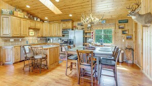 A wooden cabin interior with a kitchen, dining area, and a mounted deer head. - On 4 Acres! Retreat w/ Lake Access in Maple City (Maple City)