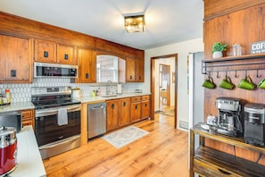 A kitchen with wooden cabinets, stainless steel appliances, and a coffee station. - Bring the Family! Mid-century Modern Gem in Euclid (Euclid)