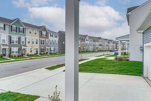 Une rangée de maisons de ville, avec une rue devant, un trottoir et une zone herbeuse.