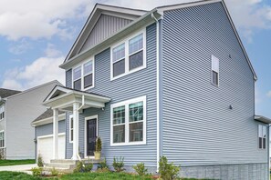 Une maison d’habitation à deux étages, dotée d’un porche à l’avant, d’un garage et d’un petit jardin devant.