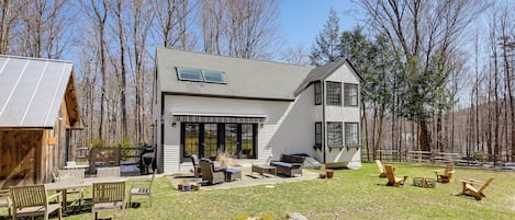 A modern house with a patio, outdoor seating, and a fire pit.