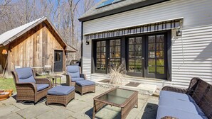 A wooden cabin with a patio area featuring wicker furniture and a glass-top table. - Charming Dorset Cottage Nestled in the Treetops (Dorset)