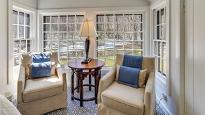 A room with two armchairs, a small table with a lamp, and large windows with a view of a snowy landscape. - Charming Dorset Cottage Nestled in the Treetops (Dorset)