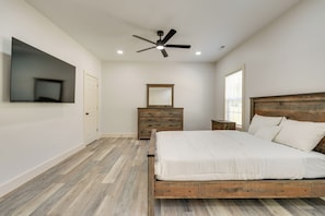 A bedroom with a bed, a dresser, a mirror, a ceiling fan, and a TV mounted on the wall. - Modern Erwin Getaway Near the AT & Nolichucky (Erwin)