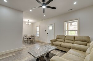 Amplia sala de estar con ventilador de techo, comedor con sillas, sofá y una mesa de centro de mármol.