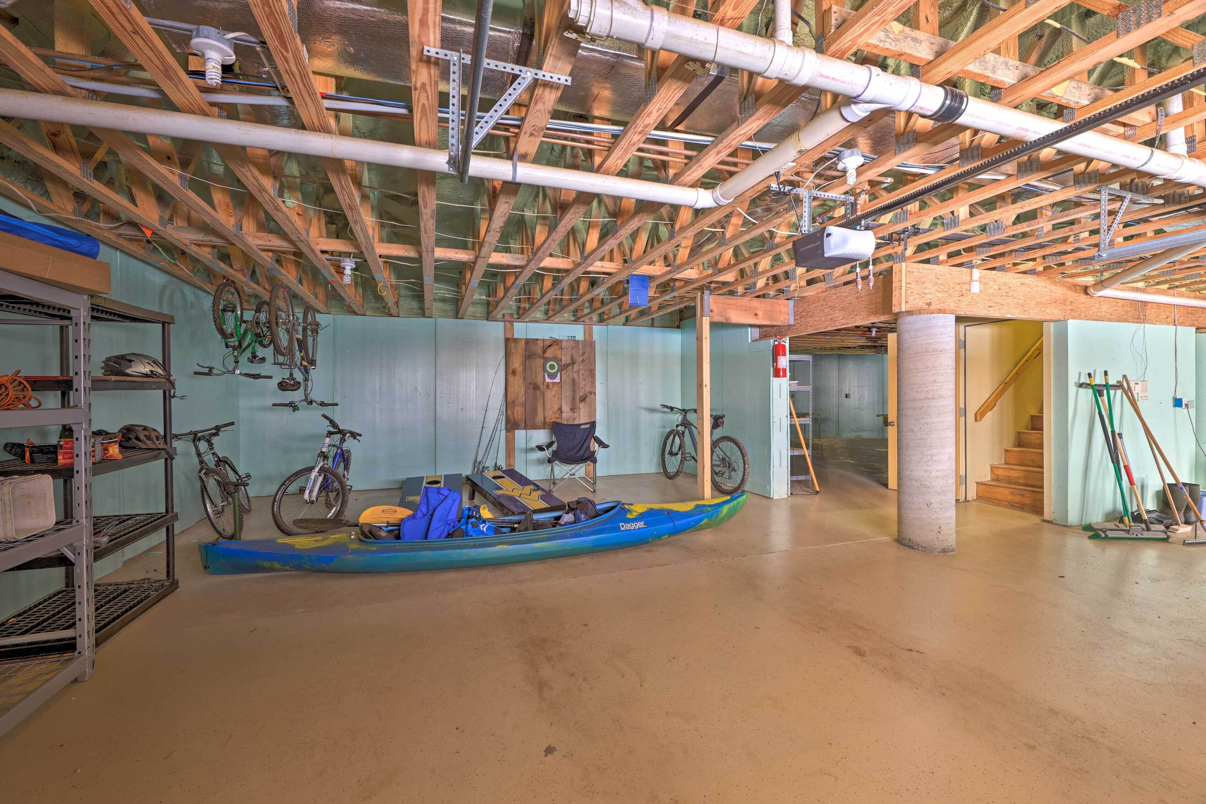 An unfinished room with exposed wooden beams and pipes, bicycles, and a canoe.