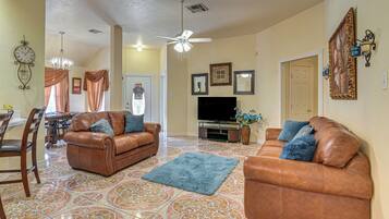 A living room with two brown leather sofas, a TV, and a patterned floor.
