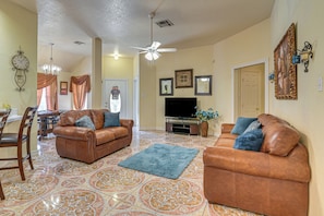 A living room with two brown leather sofas, a television, and patterned floor tiles.